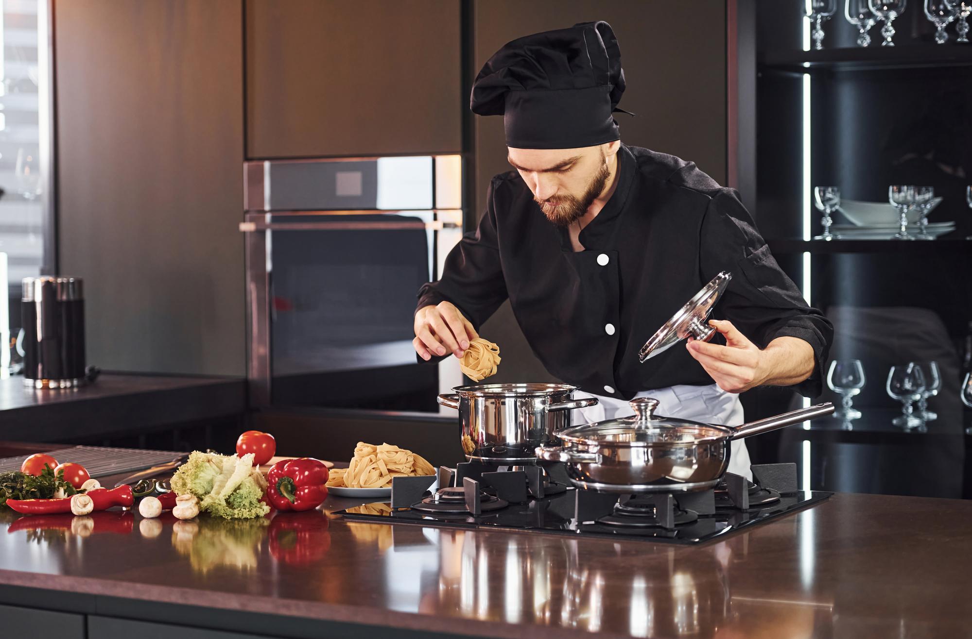 Chef in cucina moderna con attrezzatura professionale